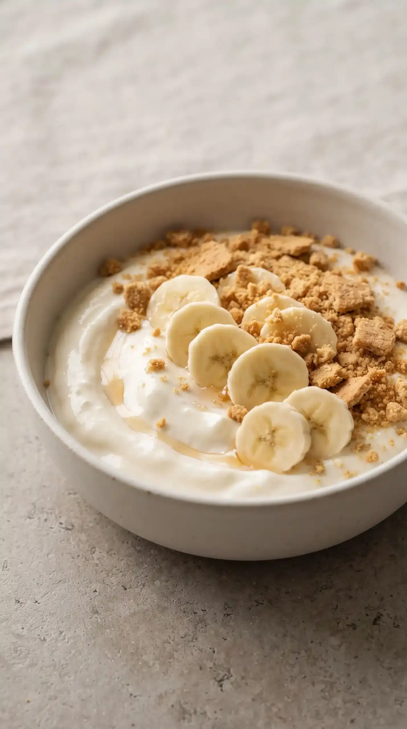 Finished banana pudding yogurt bowl topped with banana slices and graham cracker crumbs