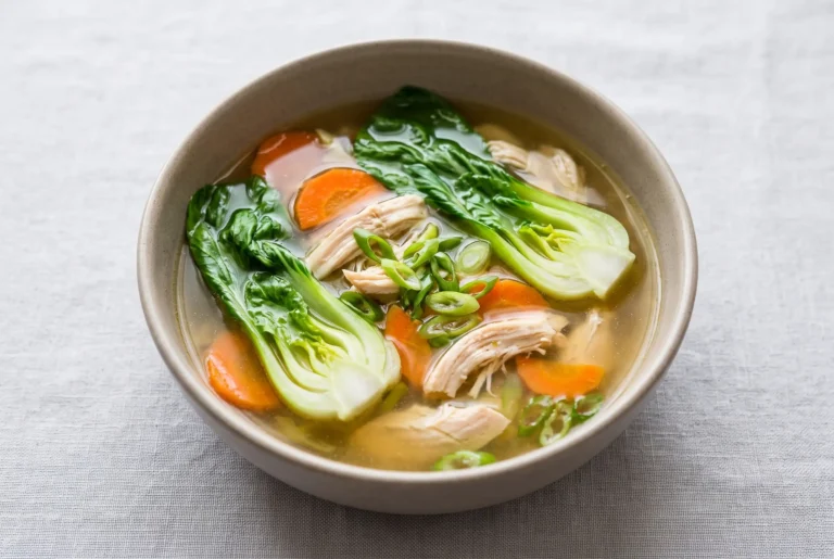 Bowl of bok choy chicken soup with garlic ginger broth, chicken, vegetables, and green onions