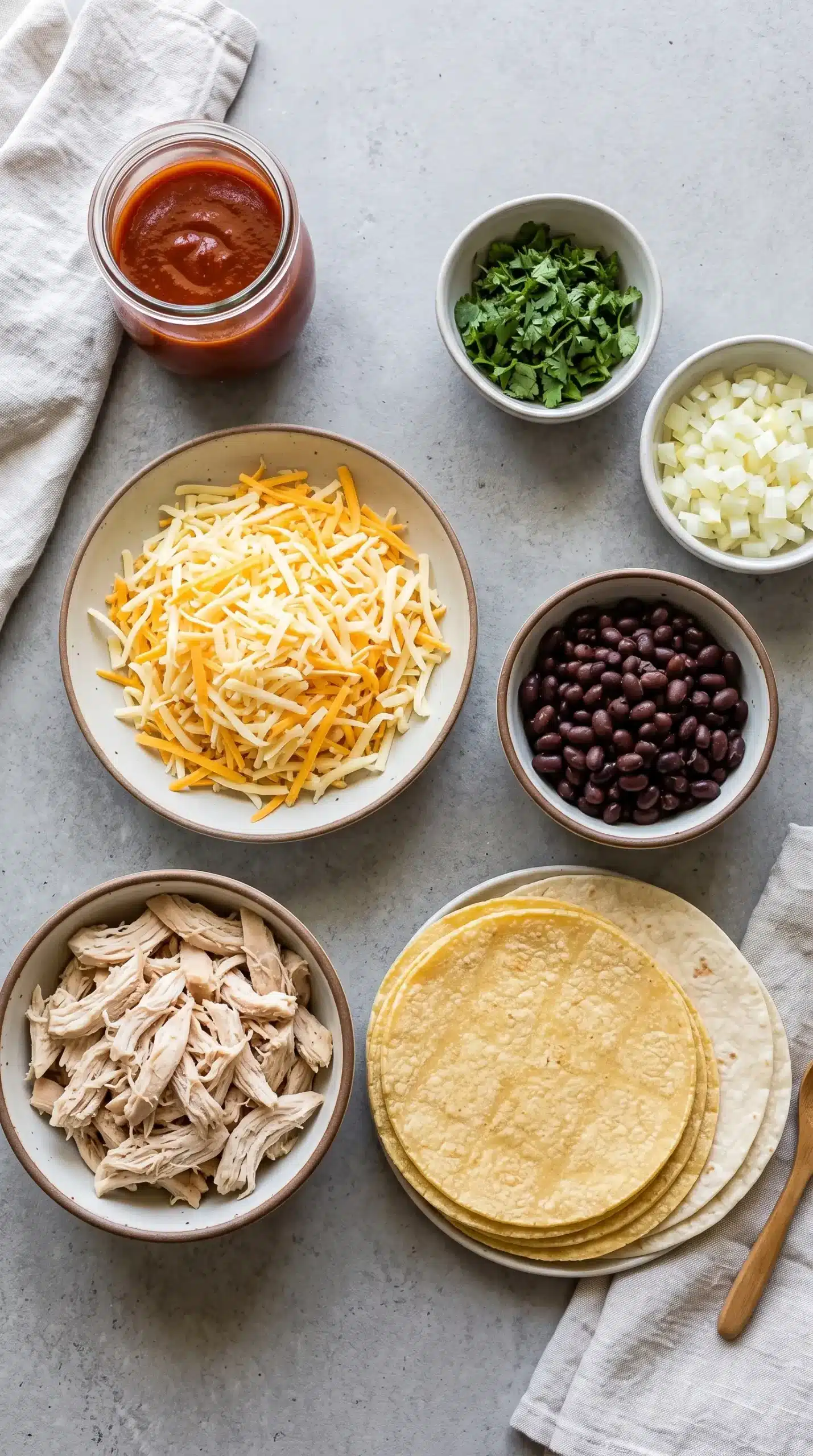 Ingredients for chicken enchiladas including shredded chicken, tortillas, sauce, and cheese