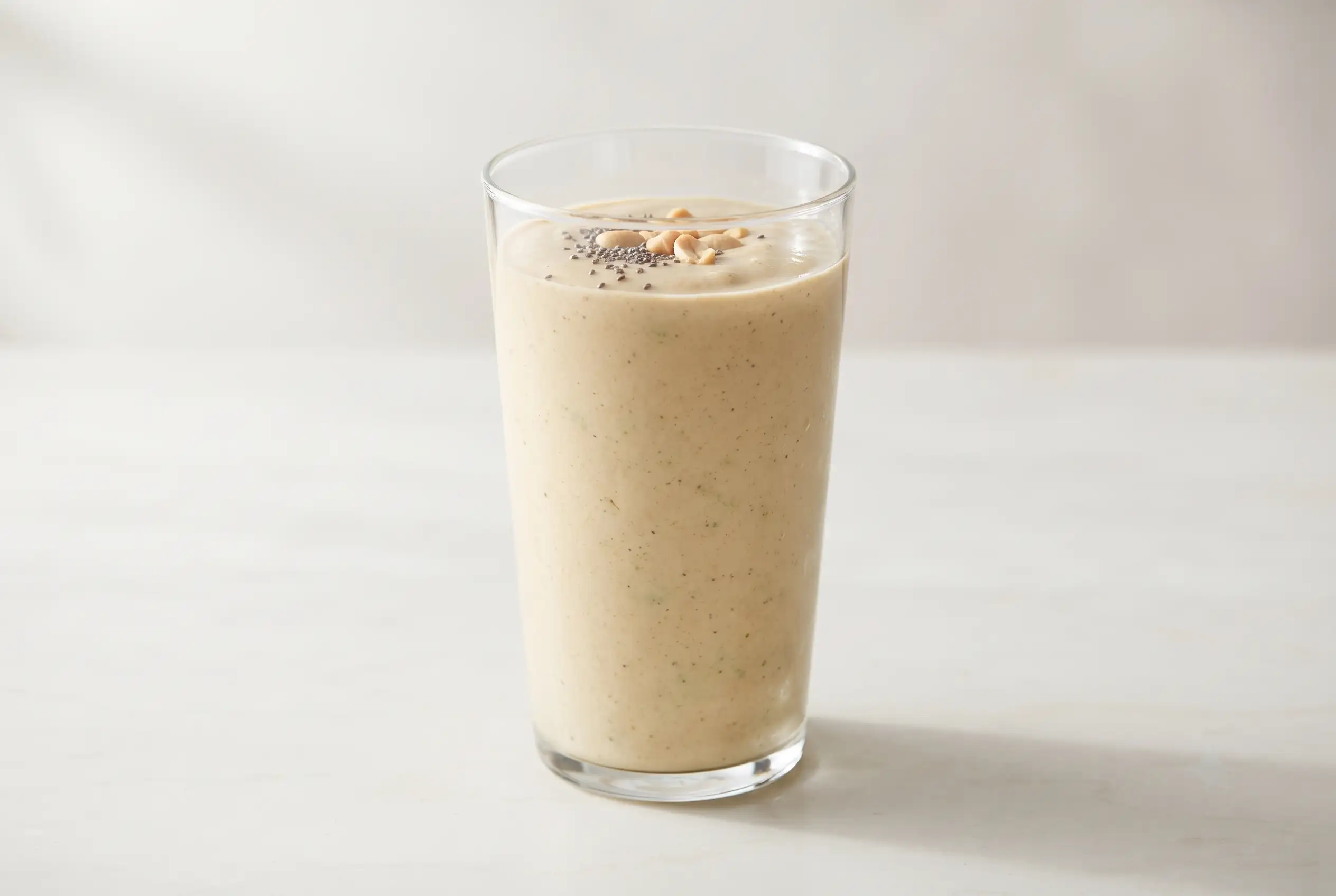 Energy boosting smoothie with banana, peanut butter, spinach, and chia seeds in a clear glass