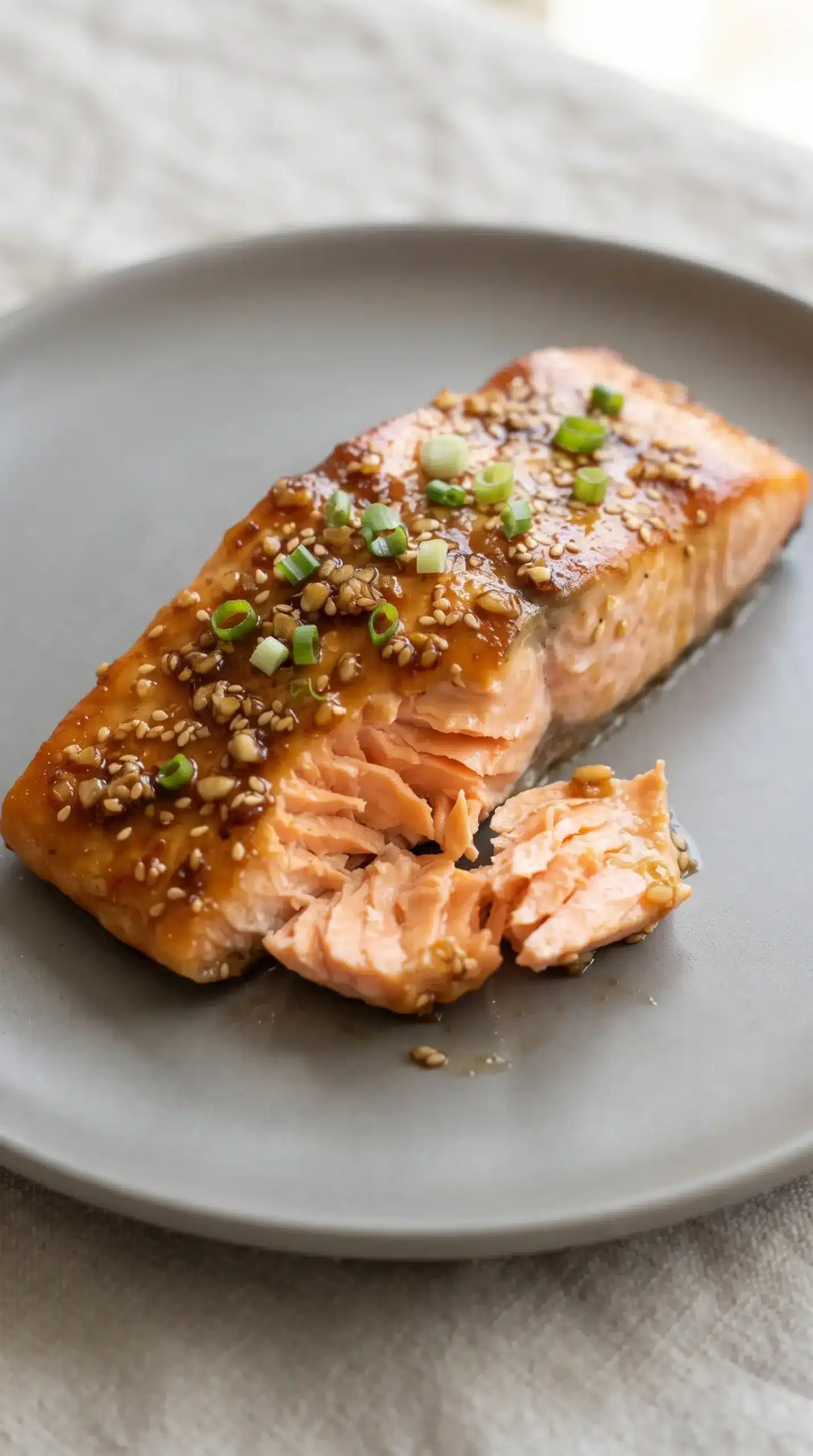 Plated baked honey garlic salmon fillet with flaky texture and green onion