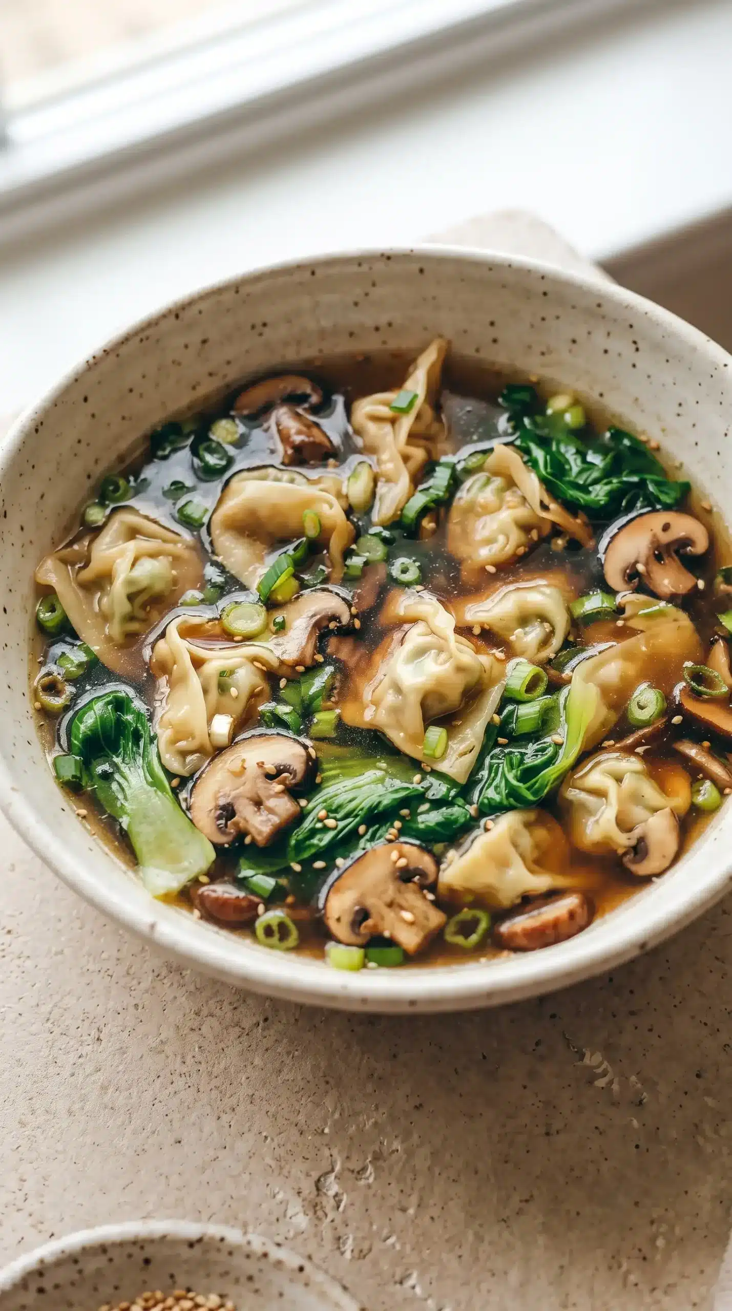 Finished potsticker soup bowl with dumplings, savory broth, greens, and green onion garnish