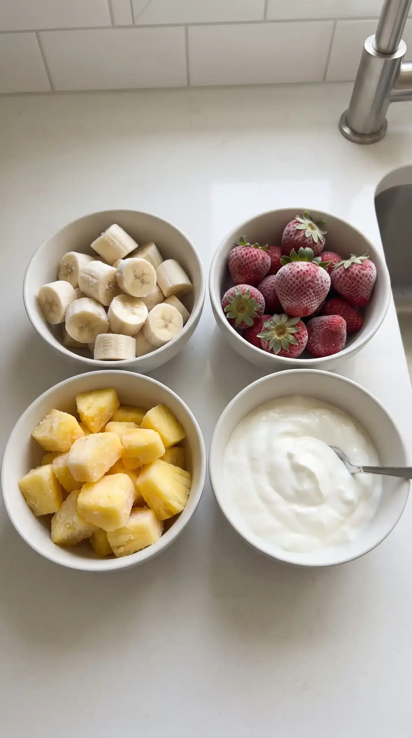 Frozen banana, strawberries, pineapple, and Greek yogurt prepared for a smoothie bowl base