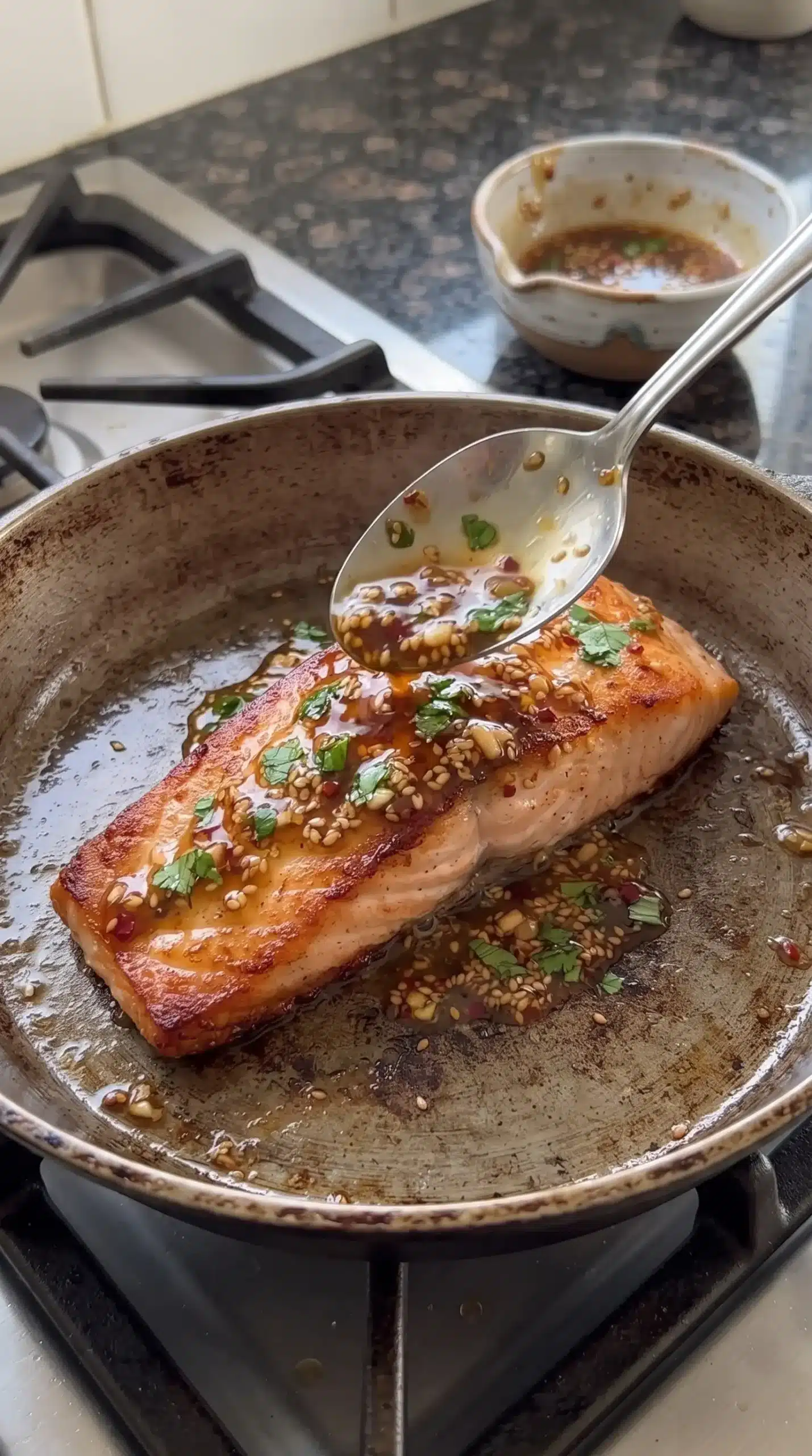 Salmon fillet searing in a skillet while coated with honey garlic glaze