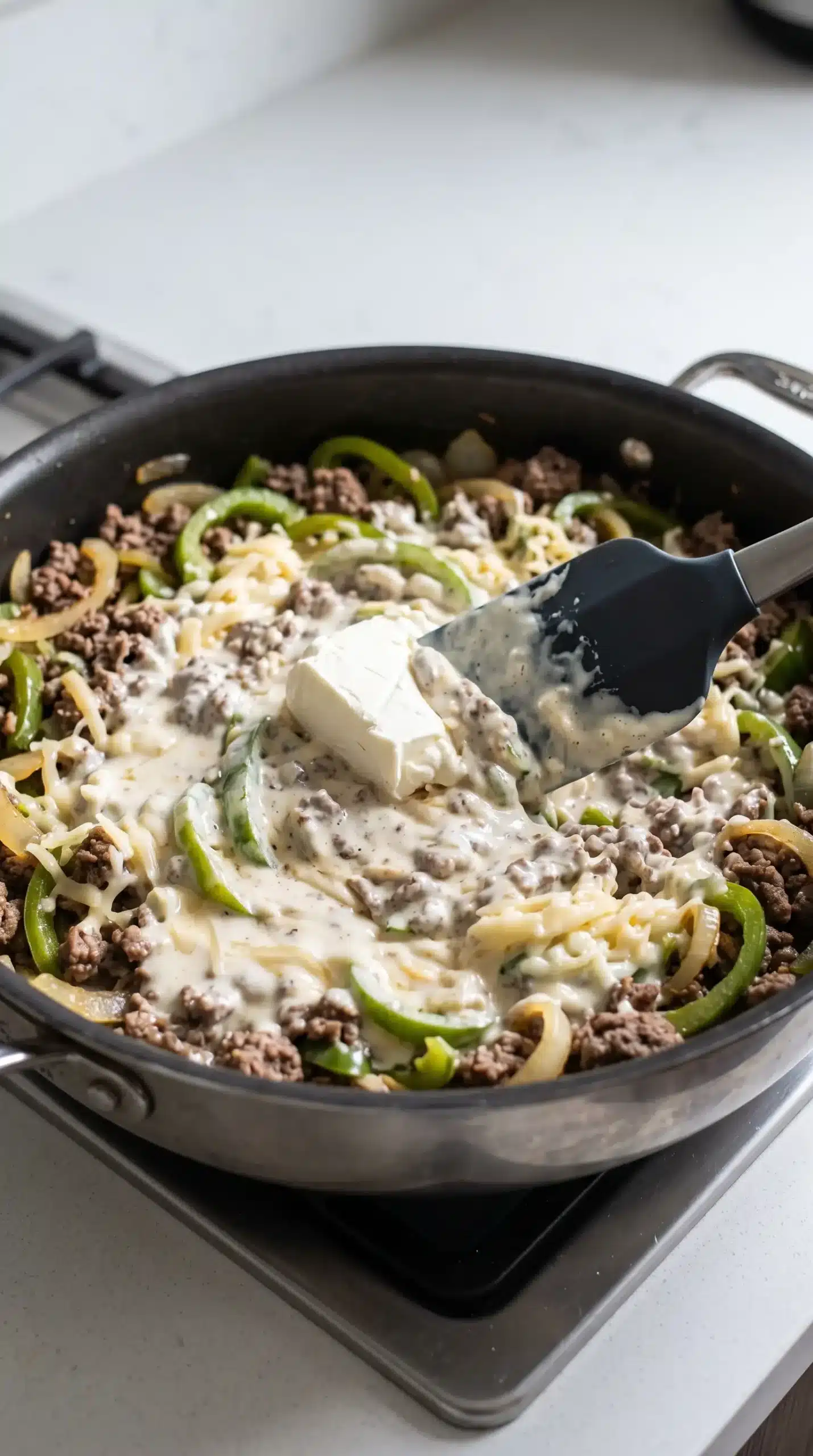 Ground beef, peppers, onions, and cream cheese combined in a skillet for casserole filling