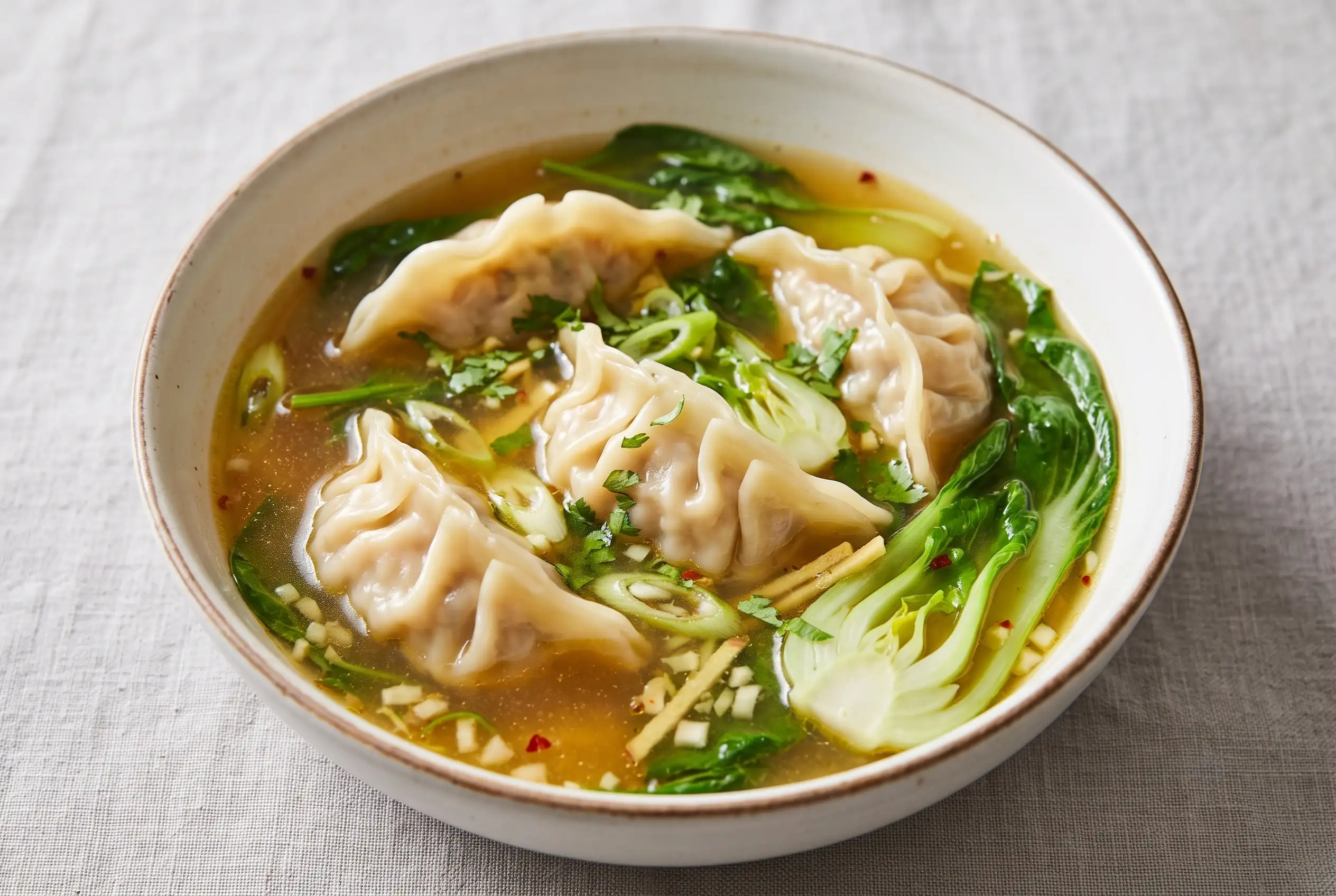 Potsticker soup with tender dumplings, greens, and savory broth in a ceramic bowl