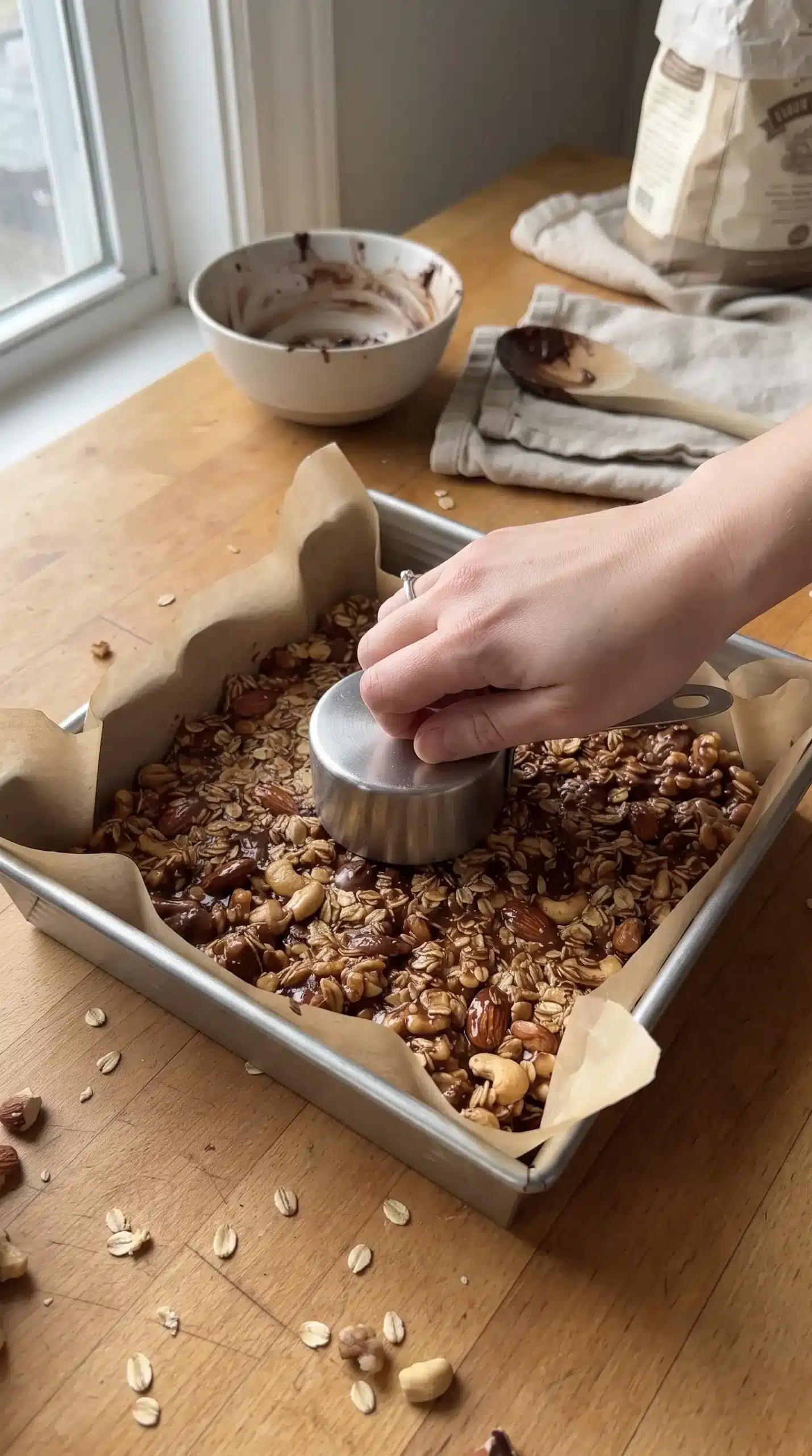 Nut bar mixture pressed firmly into a parchment-lined baking pan before slicing