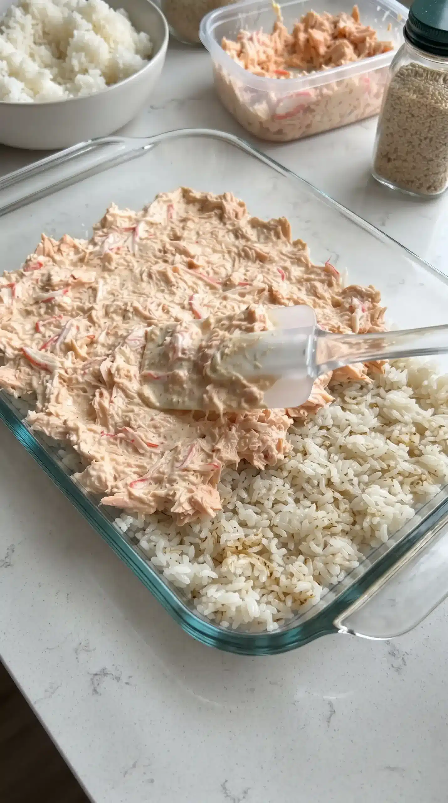 Layering sushi rice, salmon, and crab mixture in a baking dish for sushi bake