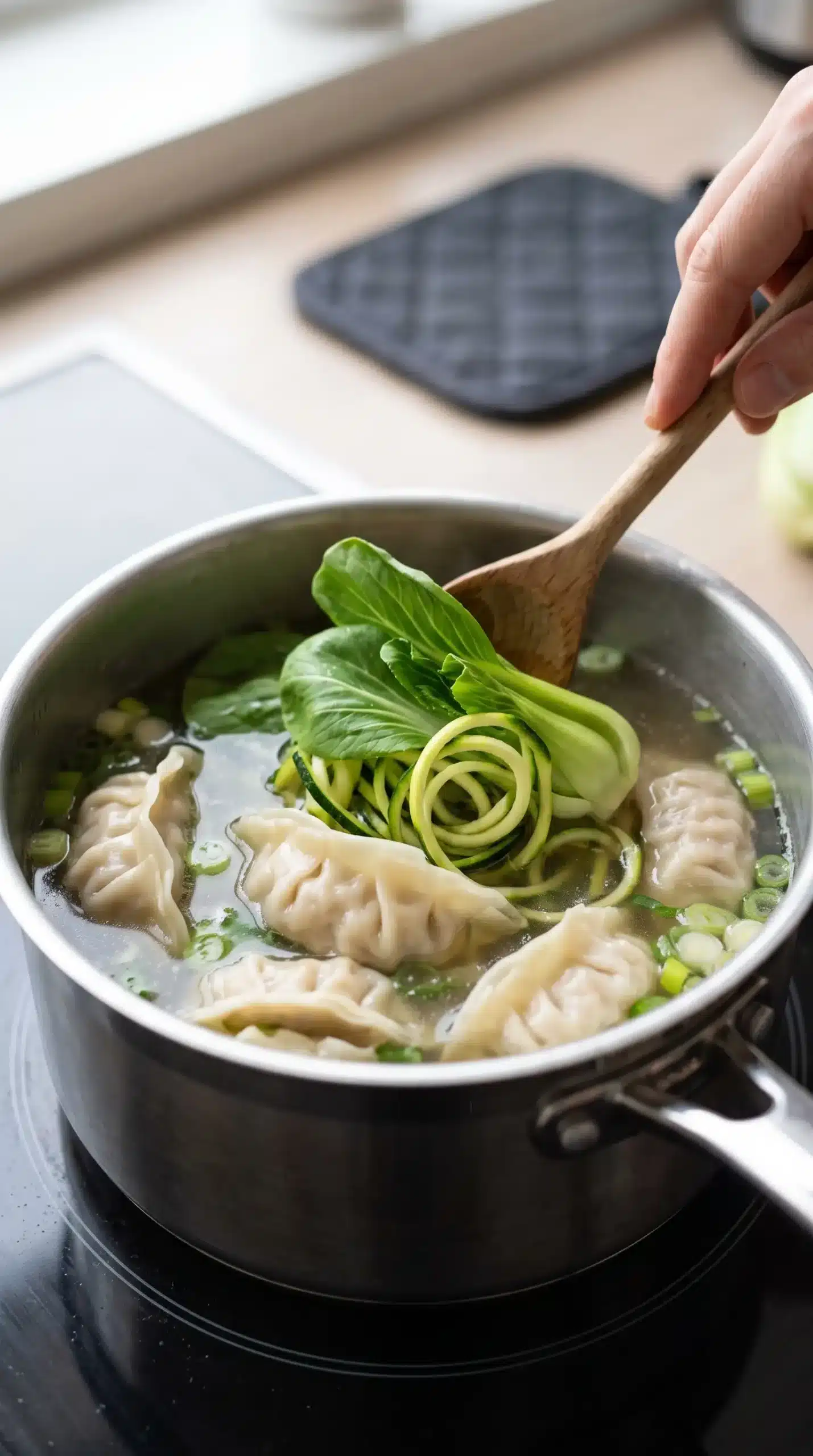 Gyoza dumplings simmering with pak choi and courgette in savory broth