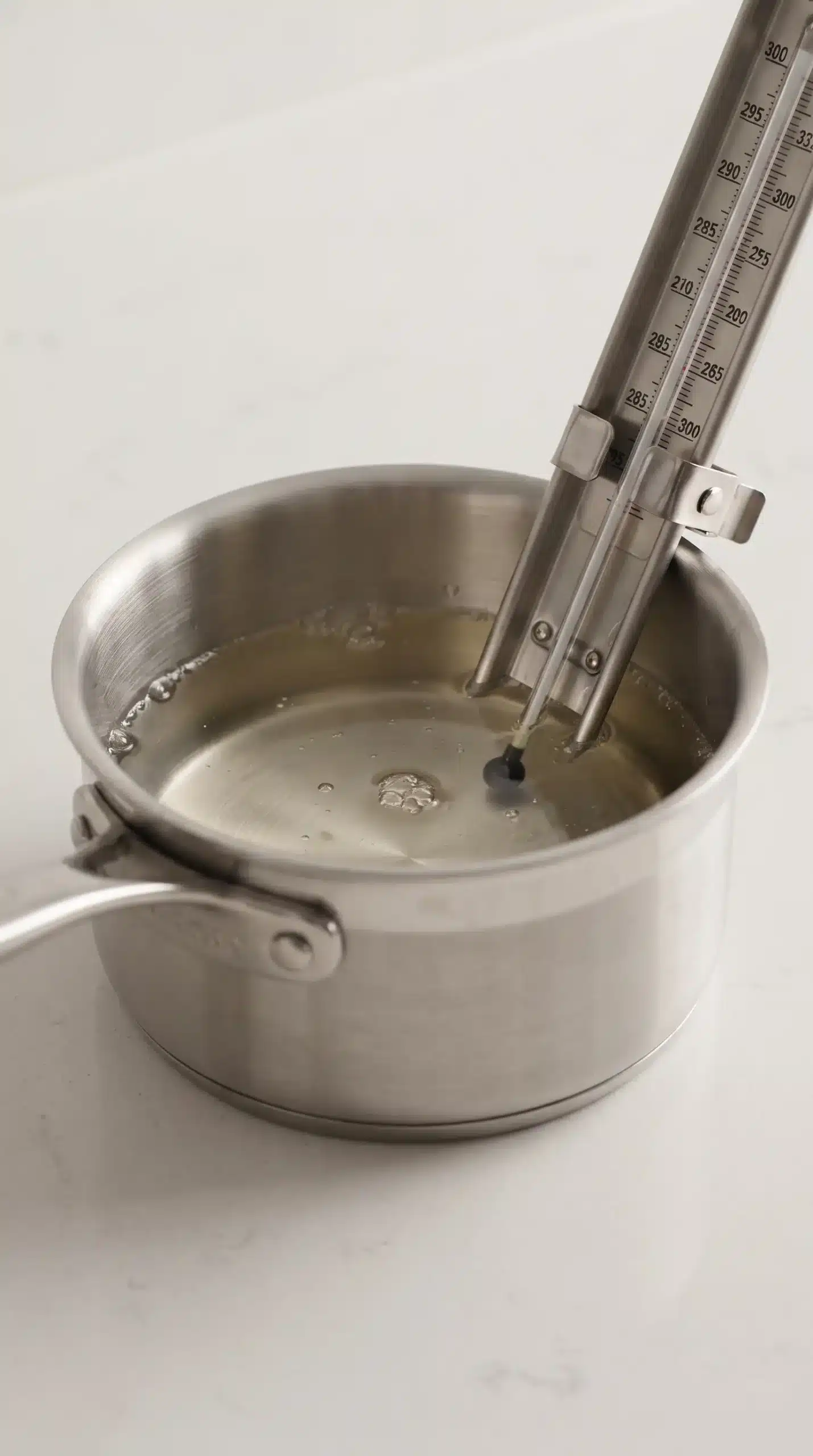 Sugar syrup heating in a saucepan with a candy thermometer for tanghulu coating